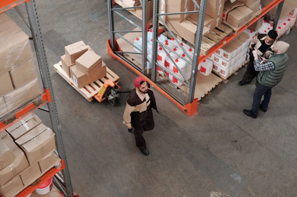 Team working in an industrial warehouse discussing and organizing inventory with pallets.