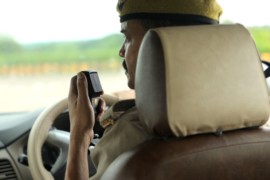 A police officer communicates via radio in a patrol car, maintaining public safety.